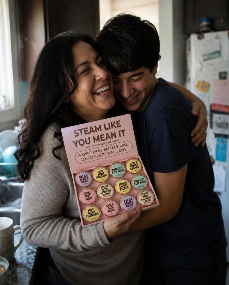A laughing mother hugging her teenage son in the family kitchen, the Mesmos Mom Series box in her hand