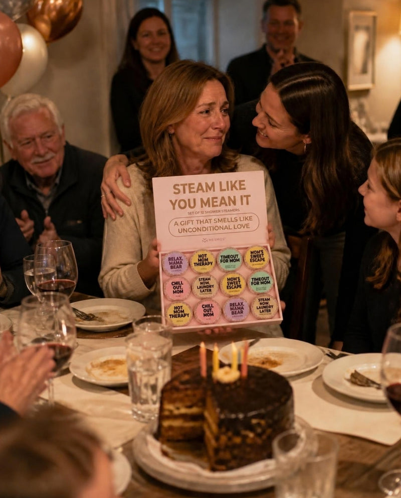 A mother at her family birthday dinner holding the open Mesmos Mom Series box while her daughter hugs her