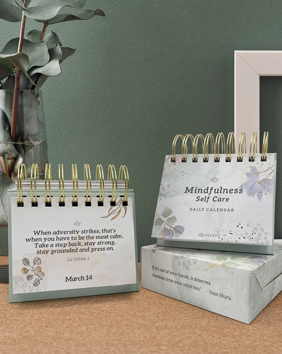 The Mindfulness Self Care flip calendar open on a shelf beside eucalyptus and a picture frame.