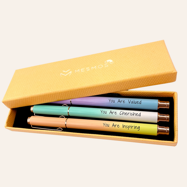 Three pastel pens in an open mustard yellow Mesmos gift box, engraved You Are Valued, You Are Cherished and You Are Inspiring.
