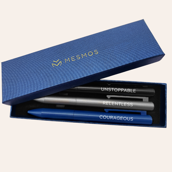 Three dark metal pens in an open navy Mesmos gift box, engraved Unstoppable, Relentless and Courageous.
