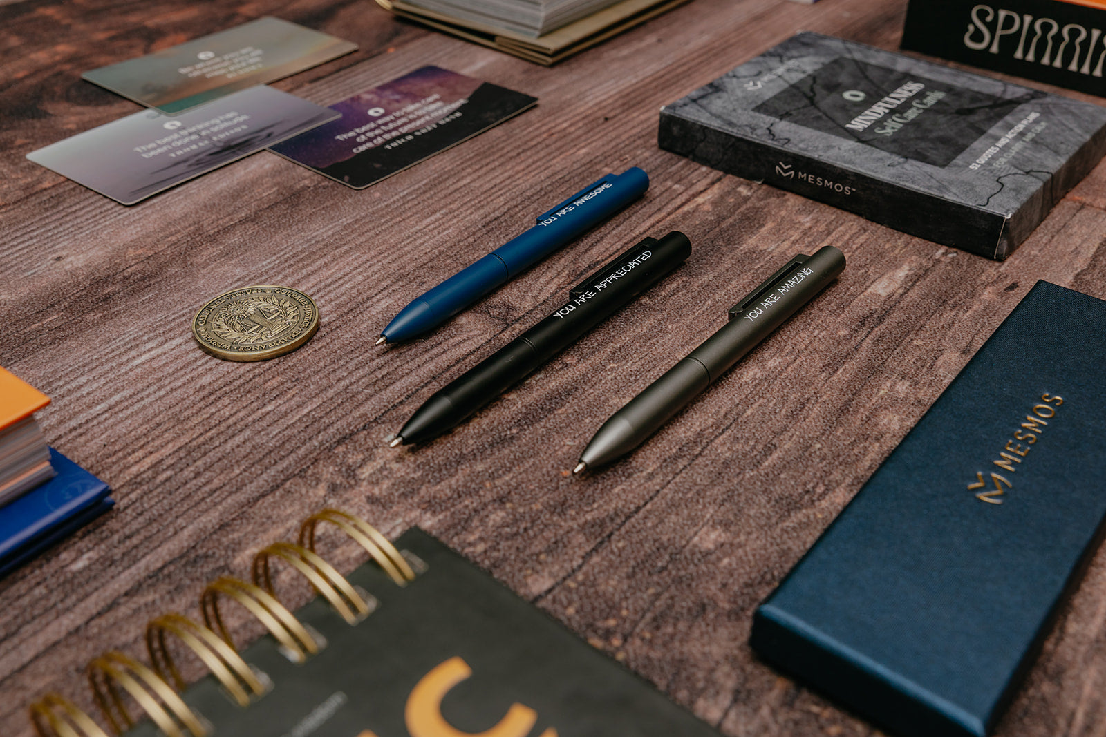 Pens, notebooks, and other stationery items on a wooden surface