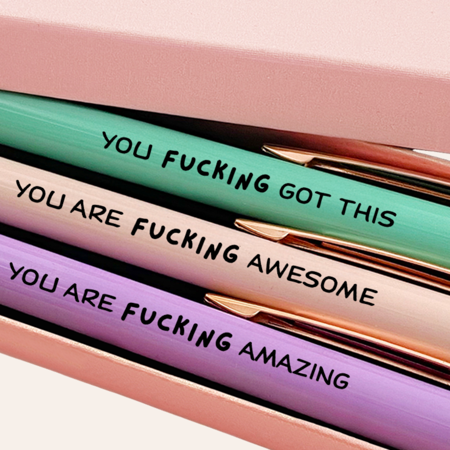 Three pens with motivational phrases in a pink box, featuring the brand 'MESMOS'.