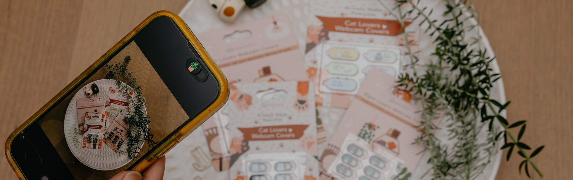 Phone displaying a circular design on a table with printed materials and a plant.