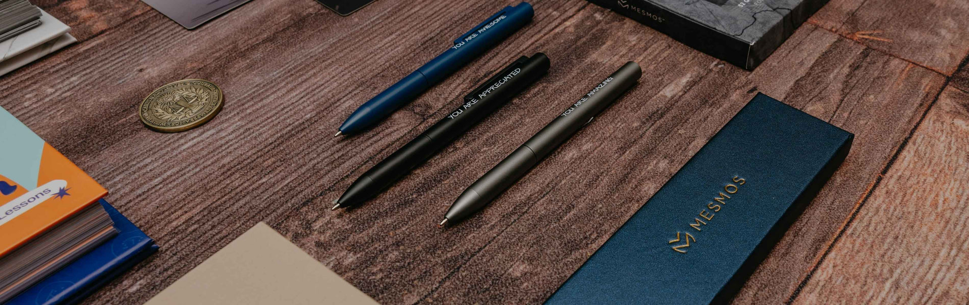 Pens and a notebook on a wooden surface